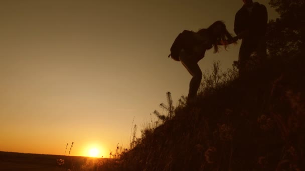 Avventura e concetto di viaggio. I turisti scendono dalla montagna al tramonto, tenendosi per mano. viaggiatore maschio tiene la mano di un viaggiatore femminile che scende dalla cima della collina. lavoro di squadra di uomini d'affari . — Video Stock