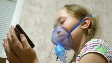 Tabletli çocuk hasta ve astım spreyinden nefes alıyor. Yakın plan. Hastanede yüzünde solunum maskesiyle tedavi edilen küçük bir kız. Yürümeye başlayan çocuk, solunum buharı soluyarak grip tedavisi görüyor..