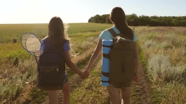 Concepto turismo y viajes. trabajo en equipo turistas adolescentes. Las mujeres viajeras caminan por una carretera en el campo. chica excursionista feliz en el parque de verano. Feliz niñas viajeros van con mochilas en el campo . — Vídeo de stock