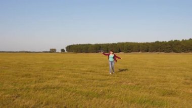 Mutlu çocukluk kavramı. Mutlu kız oyuncak uçakla sahada koşuyor. Çocuklar oyuncak uçak oynuyorlar. Gençler uçmayı ve pilot olmayı hayal eder. Kız pilot ve astronot olmak istiyor. Yavaş çekim.