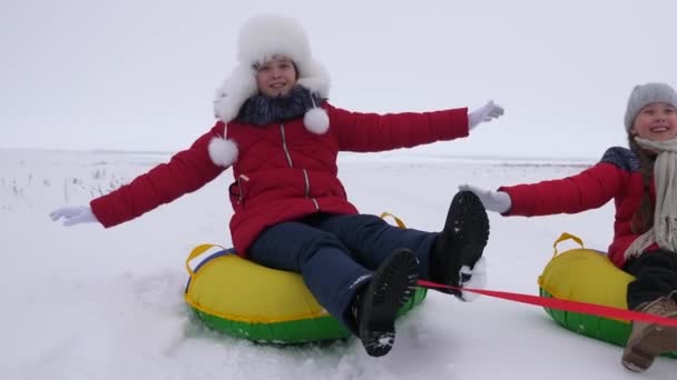 幸せな子供時代のコンセプト。幸せな子供たちは雪の山に乗って、飛行中に腕をまっすぐにし、笑っています。そりで冬の幸せな子供時代。クリスマス休暇幸せな家族の概念 — ストック動画