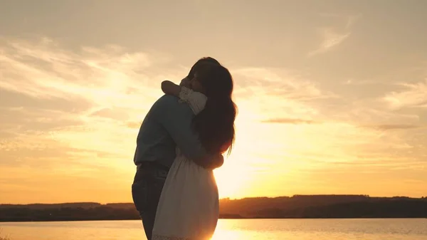 Feliz chico y chica vals en la noche en el parque de verano. Hombre y mujer cariñosos bailan en brillantes rayos de sol en el fondo del lago. Pareja joven bailando al atardecer en la playa . —  Fotos de Stock