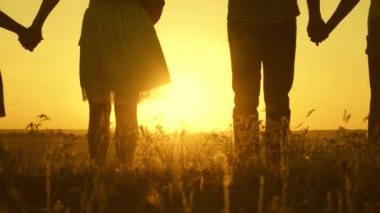 Mutlu büyük aile gün batımında tarlada yürür ve güler. Ebeveynler ve üç çocuk akşam parkta yürürler. Özgür büyük bir aile kavramı. Tatil ve seyahat. Yavaş çekim