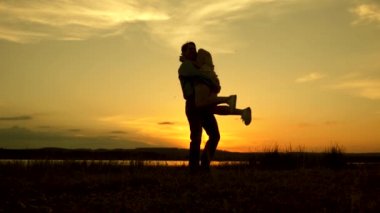 Sevgi dolu erkek ve kadın gölün arka planda güneşin parlak ışınları dans. Genç çift sahilde gün batımında dans ediyor. Yaz parkında akşam mutlu adam ve kız vals.