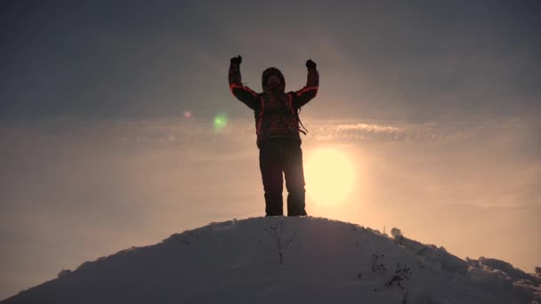 Viaggiatore dell'Alaska andare in cima a una collina innevata e gioire della vittoria contro un tramonto invernale. Alpinista Viaggio in montagna in inverno. L'alpinista fa escursioni. Viaggiatore sale una vetta di montagna . — Video Stock