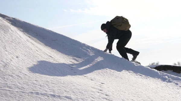 Человек поднимается на вершину своего успеха. Альпинист карабкается на снежную гору в лучах яркого солнца. турист поднимается на вершину на фоне красивого неба. — стоковое фото