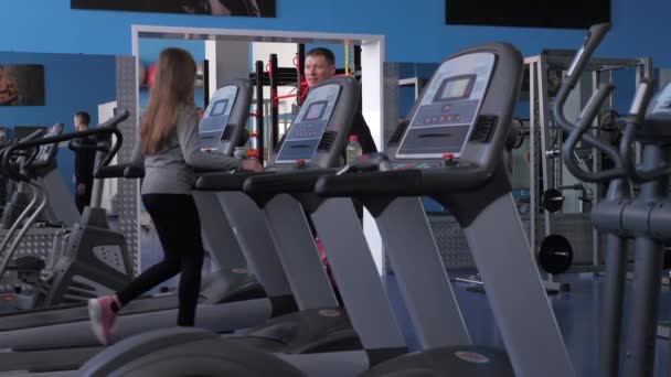 Girl is training on a treadmill under supervision of a trainer. Strengthening muscles of legs when walking. cardio load. Fitness club woman goes for walks. Sport lifestyle concept. weight loss in gym. — Stock Video