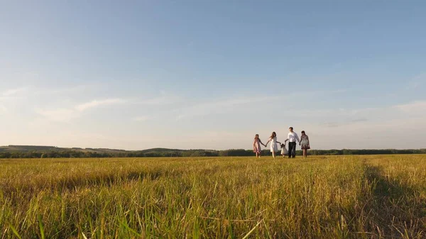 Children, dad and mom play in meadow in the sunshine. mother, father and little daughter with sisters walking in field in the sun. Happy young family. concept of a happy family. — 스톡 사진