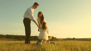Anne ve baba küçük kızına çimlerin üzerinde bisiklet sürmeyi öğretiyor. Babam çimenlikte küçük çocukla oynuyor. Çocuk bisiklet sürmeyi öğreniyor. Mutlu aile ve çocukluk kavramı.