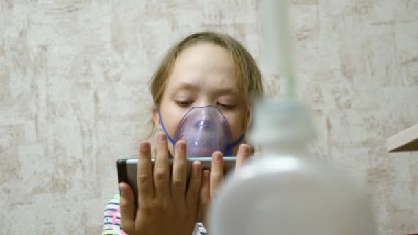 Το παιδί με δισκίο είναι άρρωστο και αναπνέει μέσω ενός εισπνευστήρα. Κοντινό πλάνο. Κοριτσάκι θεραπευμένο με μάσκα εισπνοής στο πρόσωπό της στο νοσοκομείο. Το βρέφος αντιμετωπίζει τη γρίπη εισπνέοντας ατμούς εισπνοής. — Αρχείο Βίντεο