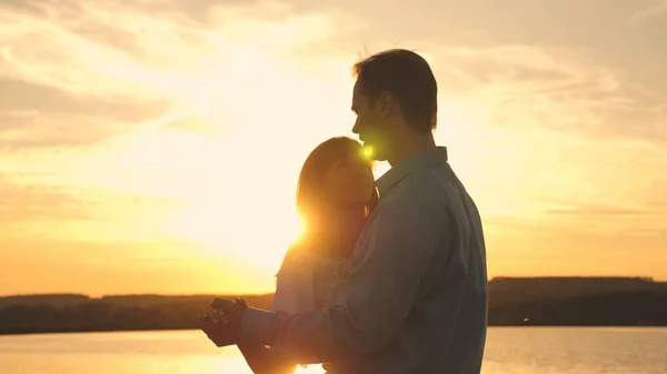 Jeune couple dansant au coucher du soleil sur la plage. Un homme et une femme aimants dansent dans des rayons de soleil lumineux sur le fond du lac. Heureux gars et fille valse dans la soirée dans le parc d'été . — Photo