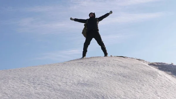 Der Mensch rückt zu seinem Erfolg an die Spitze. Bergsteiger erklimmt schneebedeckten Berg in Strahlen der strahlenden Sonne. Tourist macht Aufstieg nach oben auf dem Hintergrund des schönen Himmels. — Stockfoto