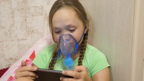 Child with tablet is sick and breathes through an inhaler. close-up. little girl treated with an inhalation mask on her face in hospital. Toddler treats flu by inhaling inhalation vapor. — Stock Video