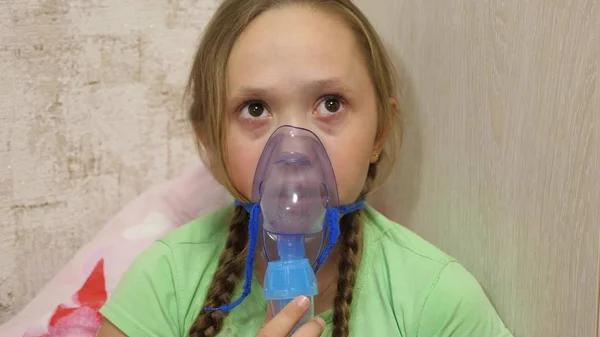 El niño con el comprimido está enfermo y respira a través de un inhalador. Primer plano. niña pequeña tratada con una máscara de inhalación en su cara en el hospital. El niño pequeño trata la gripe inhalando vapor de inhalación . — Foto de Stock