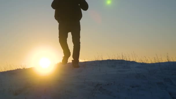 Alpiniste voyage randonnée. Un voyageur descend sur une montagne enneigée depuis le sommet, au coucher du soleil. touriste va à la victoire surmonter les difficultés. voyageur descend la pente enneigée à une colline enneigée au soleil . — Video