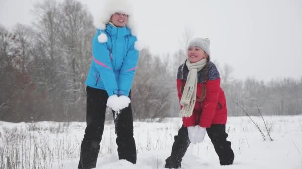 Happy childhood concept. family plays in winter park for christmas vacation. mother and daughter throw snow up. Mom and baby have fun in winter forest. Slow motion. concept of life of a large family — Stock Video