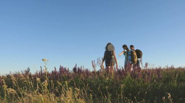 Turistlerin takım çalışması. Gezginler sırt çantalarıyla çayıra giderler. Kırsalda çocuklu bir turist ailesi. Gezginler güzel manzaraya ve doğaya hayran kalırlar. Zafere giden yol.