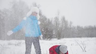 Mutlu anne ve kız kar yağdırır, kar yağar ve ışıldar. Aile Noel tatili için kış parkında oynuyor. Anne ve bebek kış ormanında eğleniyor. Yavaş çekim