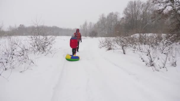 Pappa och dotter går genom en snöig skog. Turister vandrar på vintern. Julhelger. Familjen reser i vita snödrivor. Livsstil — Stockvideo