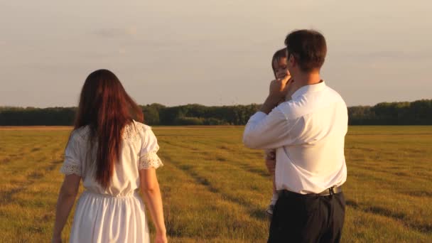 Familia feliz con hija pequeña jugar y reír al atardecer. Mamá y el bebé en los brazos del Papa está lleno de risas en vuelo. El padre lleva un niño pequeño en sus brazos, y la madre envía un beso — Vídeos de Stock