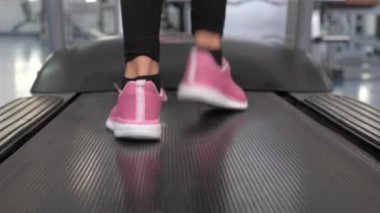 Spor ayakkabılı kızın bacakları koşu bandına kadar uzanıyor. Yakın plan. Yürürken bacak kaslarını güçlendiriyor. Kardiyo yüklemesi. Spor salonundaki kadın yürüyüşe çıkıyor. Spor yaşam tarzı konsepti. Spor salonunda kilo kaybı.