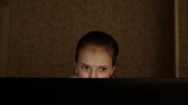 Yorgun genç kız bir dizüstü monitör ekrana bakar. Close. Genç bir kız gece odasında yorgun gözleri ile bilgisayar ekranına bakar. yorgun genç kız bir dizüstü monitör ekrana bakar.