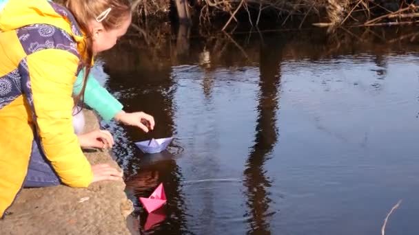 Dospívající dívky posílají papírové barevné lodě v plavání. Dětské hry a zábava. Dětský život — Stock video