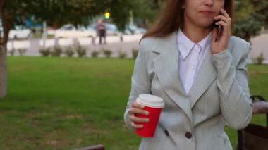 iş kadını smartphone üzerinde konuşmak ve parkta kahve içme ışık takım elbiseli gözlüklü