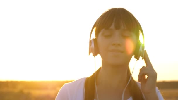 Νεαρή κοπέλα σε ακουστικά περπατώντας κατά μήκος του δρόμου, ακούγοντας μουσική και χορό — Αρχείο Βίντεο
