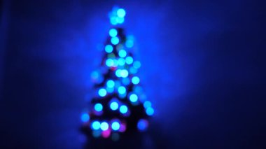Odada parlak bir çelenk ve yıldızla süslenmiş çok renkli bir yılbaşı ağacı var. Çocuklar ve yetişkinler için tatil. Yeni yıl. Noel ağacı, mutlu tatiller. Noel arşivi.