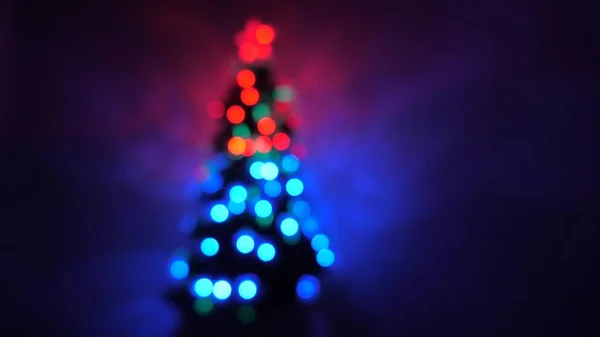 Mehrfarbiges Bokeh eines Neujahrsbaumes im Raum, dekoriert mit leuchtenden Girlanden und einem Stern. Urlaub für Kinder und Erwachsene. Neujahr. Weihnachtsbaum, frohe Feiertage. Weihnachtsdekoration. — Stockfoto