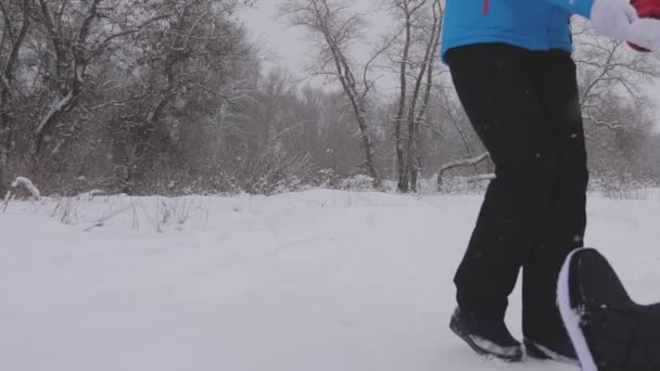 Egy boldog család fogalma. gyermek és anya szánkóztak apjukkal a hóban. a boldog gyermekkor fogalma. A lányok apával játszanak a téli parkban a karácsonyi szünetben. családi téli vakáció. — Stock videók