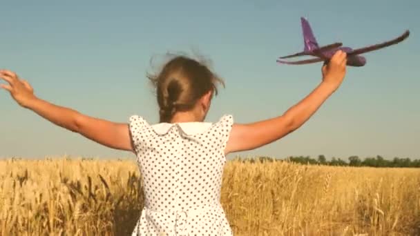Szczęśliwa dziewczyna biegnie z zabawkowym samolotem na polu w świetle zachodu słońca. Dzieci bawią się w zabawkowy samolot. nastolatek marzy o lataniu i zostaniu pilotem. Dziewczyna chce zostać pilotem i astronautą. Zwolniony ruch — Wideo stockowe
