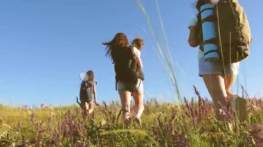 Gezginler sırt çantalarıyla çayırlara giderler. Anne ve kızları, küçük bir bebek yaz aylarında sırt çantalarıyla tarlalarda geziyor. Turist kızlar ve küçük bir bebek kampa gider. Takım çalışması gezginleri