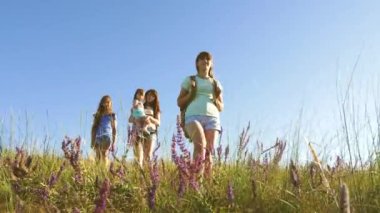 Mutlu anne ve kızları, yaz aylarında sırt çantaları renkli küçük bir bebek gezisi. Aile hayatı. Turist kızlar ve küçük bir bebek ormanda kamp yapmaya giderler. Takım çalışması gezginleri