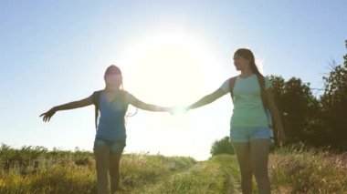 Takım çalışması turistleri. Kadın gezginler kırsalda bir yolda yürürler. Yaz parkındaki mutlu yürüyüşçü kız. Mutlu kız gezginler sırt çantalarıyla gezerler. Tatildeki genç kız maceraları.