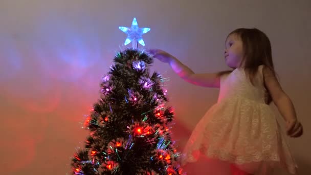 Πολύχρωμο bokeh ενός δέντρου Πρωτοχρονιάς στο δωμάτιο, διακοσμημένο με φωτεινή γιρλάντα και ένα αστέρι. διακοπές για παιδιά και ενήλικες. Πρωτοχρονιά. Χριστουγεννιάτικο δέντρο, καλές γιορτές. Χριστουγεννιάτικο εσωτερικό. — Αρχείο Βίντεο
