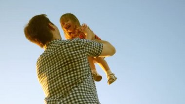 Babam bebeği mavi gökyüzüne fırlattı. Mutlu çocukluk kavramı. Babam bebeği gökyüzüne fırlatıyor. Babası küçük kızıyla parkta oynuyor. Ailesinin kış tatili. Mutlu aile kavramı.