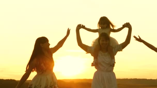 Happy childhood concept. Happy young family with a child run across field in flight at sunset light. Mother and daughters walks in park and play in the meadow in sun. concept of life of a large family — Stock Video