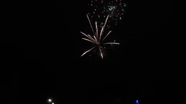 Espectáculo de fuegos artificiales brillantes. explosiones nocturnas de color en el cielo negro. hermosos fuegos artificiales multicolores en el cielo nocturno. Año nuevo víspera de celebración de fuegos artificiales. fuegos artificiales brillantes con luces bokeh en la noche — Foto de Stock