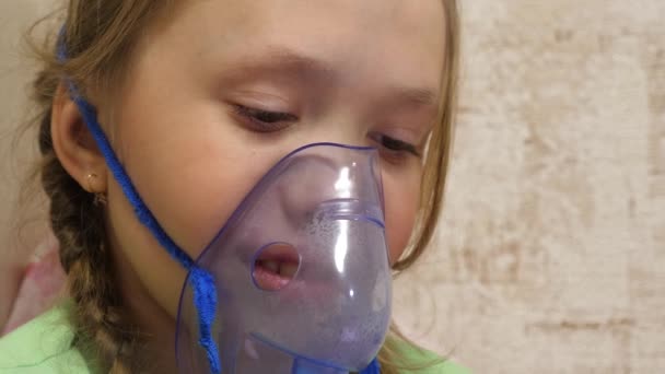 Dítě s tabletou je nemocné a dýchá přes inhalátor. detailní záběr. Holčička ošetřená s inhalační maskou na obličeji v nemocnici. Batole léčí chřipku vdechováním inhalační páry. — Stock video