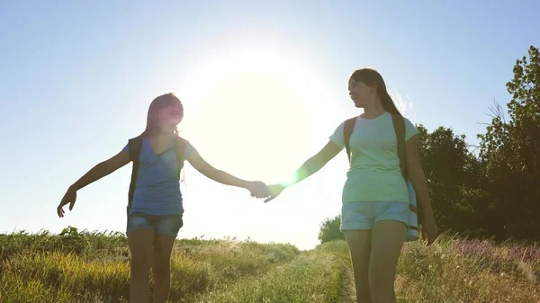 Trabajo en equipo turistas adolescentes. Las mujeres viajeras caminan por una carretera en el campo. chica excursionista feliz en el parque de verano. Las chicas felices viajan con mochilas en el campo. adolescente chica aventuras en vacaciones . — Foto de Stock