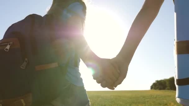 Vrouwelijke reizigers lopen over een weg op het platteland. Gelukkig wandelmeisje in het zomerpark. teamwork toeristen tieners. Gelukkige meisjes reizigers gaan met rugzakken in het veld. tiener meisje avonturen op vakantie. — Stockvideo