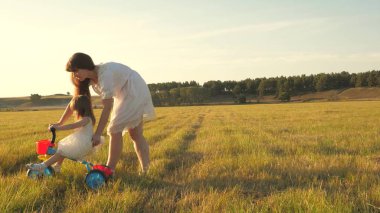 Annem kızına bisikletsürmeyi öğretir. Anne küçük kızıyla oynuyor. küçük bir çocuk bisiklete binmeyi öğrenir. mutlu çocukluk kavramı.
