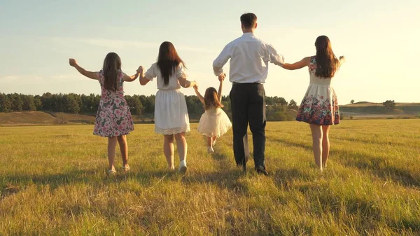 Madre, padre e hija pequeña con hermanas caminando en el campo bajo el sol. Feliz familia joven. Los niños, papá y mamá juegan en el prado bajo el sol. concepto de una familia feliz . —  Fotos de Stock