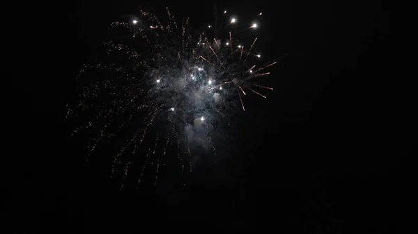 Glühendes Feuerwerk. Farbige nächtliche Explosionen am schwarzen Himmel. schönes mehrfarbiges Feuerwerk am Nachthimmel. Silvesterfeuerwerk. Leuchtendes Feuerwerk mit Bokeh-Lichtern am Nachthimmel — Stockfoto