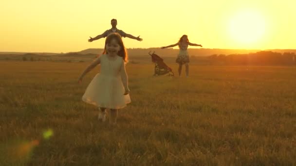 Glückliches Kind und Eltern spazieren bei Sonnenuntergang. Papa umarmt Tochter und wirbelt im Flug. Silhouette einer Familie, die in der Sonne spaziert. Mama, Papa und Baby. das Konzept einer glücklichen Familie. Familienleben — Stockvideo