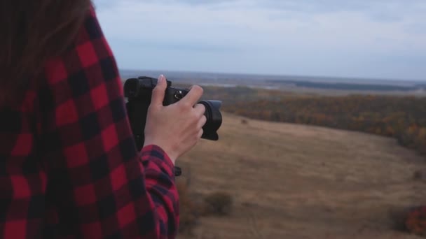 カメラ付きの女の子の旅行者は、自然の美しい写真を撮る。若い独立した女性観光客の写真家は、プロのデジタルカメラで美しい秋の風景を撮影します。旅行のコンセプト — ストック動画