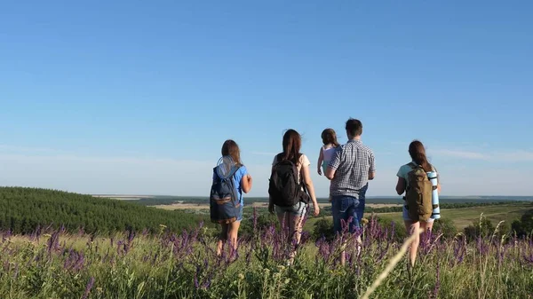 Cestovatelé obdivují krásnou scenérii a přírodu. Týmová práce turistů. cestovatelé jdou s batohy přes louku. Rodina turistů s dětmi na venkově. hnutí k vítězství. — Stock fotografie