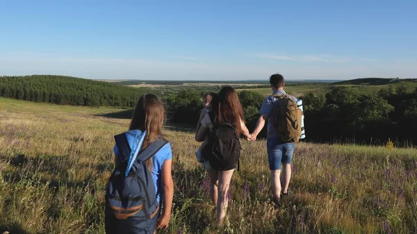 Reisende bewundern die schöne Landschaft und die Natur. Teamwork der Touristen. Reisende gehen mit Rucksäcken durch die Wiese. Touristenfamilie mit Kindern auf dem Land. Bewegung zum Sieg. — Stockfoto